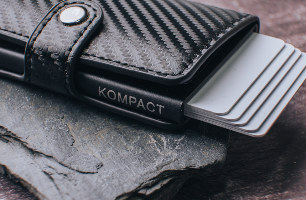 HS Kompact Carbon Fibre wallet with cards ejected on a stone base